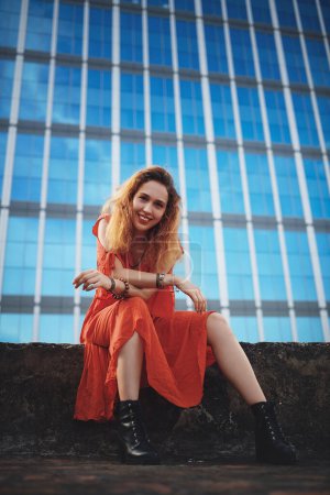 Photo for I love myself and so should you. a beautiful young woman sitting outside against a glass building - Royalty Free Image