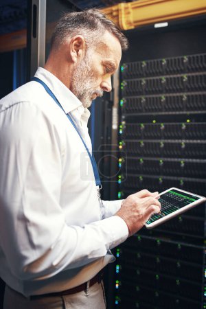 Photo for Ask the IT guy, hell tell you why. a mature man using a digital tablet while working in a server room - Royalty Free Image