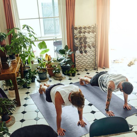 Foto de Todos los días deberían ser días de yoga. dos jóvenes haciendo tablones durante una rutina de yoga en casa - Imagen libre de derechos