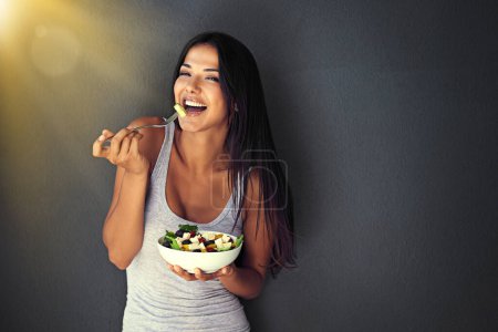 Photo for Happy woman is eating a salad, healthy food and nutrition, portrait and vegetables isolated on wall background. Organic, vegan and health with diet, female model to lose weight with mockup space. - Royalty Free Image