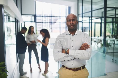 Photo for As a leader, youve got to show ambition and confidence. Portrait of a mature businessman standing in an office with his colleagues in the background - Royalty Free Image