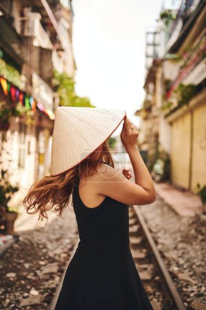 Foto de Si esperas, acabarás con remordimientos. una joven con un sombrero cónico mientras explora una ciudad extranjera - Imagen libre de derechos