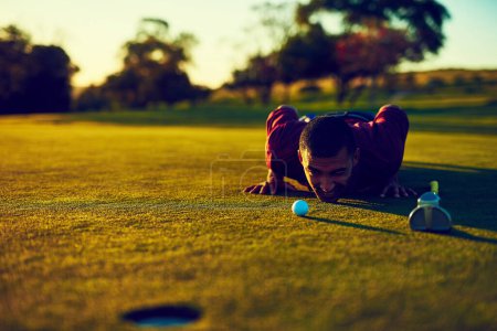 Foto de Mirando el putt perfecto. un joven mirando el putt durante una ronda de golf - Imagen libre de derechos