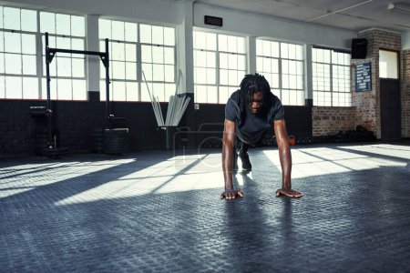Foto de El cuerpo logra lo que la mente cree. un joven haciendo flexiones en un gimnasio - Imagen libre de derechos