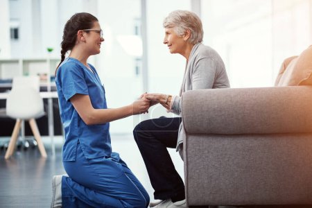 Téléchargez les photos : Comment te sens-tu aujourd'hui ? une jeune infirmière parle à sa patiente âgée à la maison de retraite - en image libre de droit
