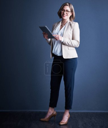 Photo for Ill use all the tools at my disposal. Studio portrait of an attractive young corporate businesswoman using a tablet against a dark background - Royalty Free Image