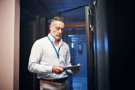 Photo for Did someone call for a wifi whiz. a mature man using a digital tablet while working in a server room - Royalty Free Image