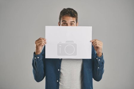 Photo for Im totally behind this. Studio portrait of a young man holding a blank placard against a grey background - Royalty Free Image
