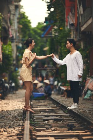 Foto de Mi corazón fue hecho para el tuyo. una joven pareja compartiendo un momento romántico en las vías del tren en las calles de Vietnam - Imagen libre de derechos