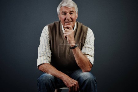 Photo for I have a lifetime of memories. Studio portrait of a handsome mature man looking thoughtful while sitting on a stool against a dark background - Royalty Free Image