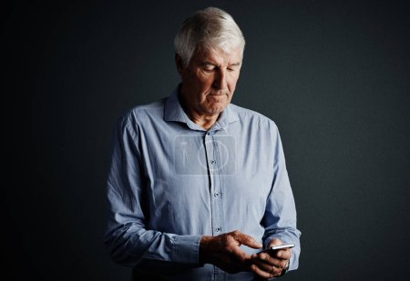 Photo for Social media isnt just for the kids. Studio shot of a handsome mature man sending a text message against a dark background - Royalty Free Image