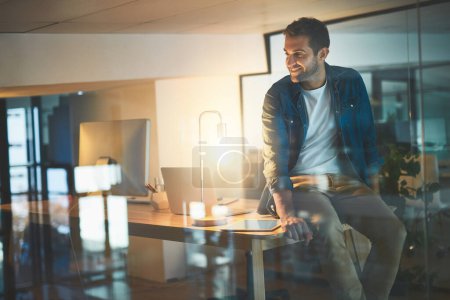 Photo for Ive never turned down a challenge. a handsome young businessman working late at night in a modern office - Royalty Free Image