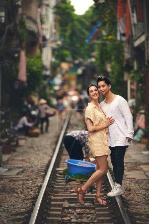 Foto de Nunca sabes dónde puedes enamorarte. una joven pareja compartiendo un momento romántico en las vías del tren en las calles de Vietnam - Imagen libre de derechos