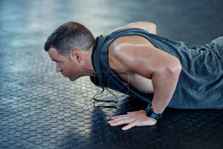 Photo for Strive for progress not perfection. a young man doing push ups in a gym - Royalty Free Image