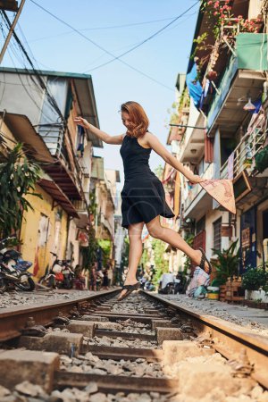 Téléchargez les photos : Faites le saut et allez vivre quelque chose de nouveau. une femme sur les voies ferrées dans les rues du Vietnam - en image libre de droit