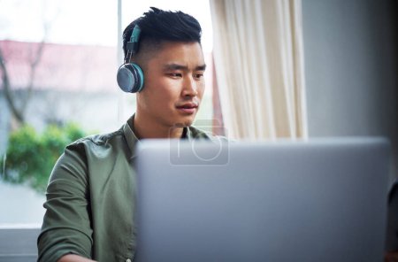 Photo for His designs are groundbreaking. a handsome young man listening to music while working from home - Royalty Free Image