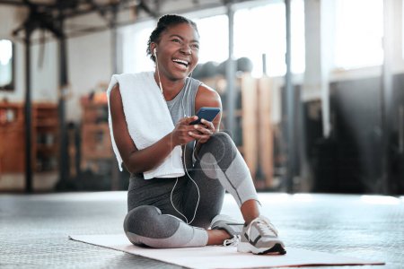 Photo for Phone, earphones and funny black woman in gym for fitness, sports or exercise. Smartphone, music and African female athlete laughing at web meme or comedy on break after workout, training or pilates - Royalty Free Image