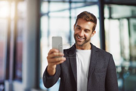 Foto de La cara del éxito. un hombre de negocios usando su celular en la oficina - Imagen libre de derechos
