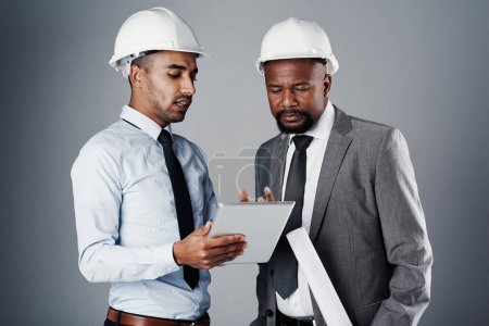 Téléchargez les photos : Ils sont attentifs aux détails. deux ingénieurs civils discutant des plans de construction alors qu'ils étaient debout dans le studio - en image libre de droit