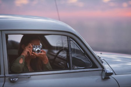 Photo for Capturing beautiful view. a young woman taking pictures while out on a road trip - Royalty Free Image