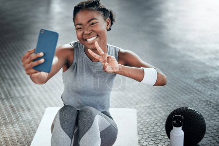 Photo for Black woman, gym selfie and peace with smile on floor for fitness, workout and wellness on social media app. Influencer girl, photography and blog for exercise, icon and health for lifestyle in club. - Royalty Free Image