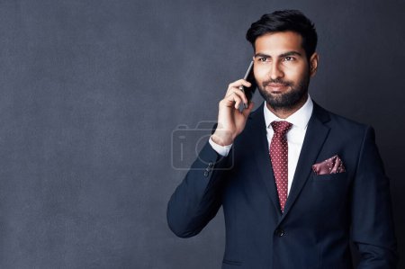 Photo for Communicating his point clearly and concisely. Studio shot of a young businessman using a mobile phone against a gray background - Royalty Free Image
