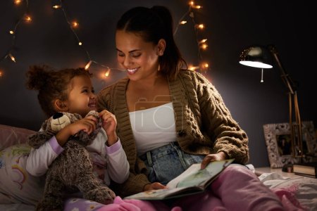 Photo for Night, book and learning with mother with daughter in bedroom for storytelling, fantasy and smile. Education, fairytale and love with woman reading to girl in family home for bedtime, happy or relax. - Royalty Free Image