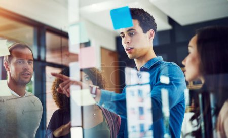 Photo for Success is their biggest priority. a group of young designers brainstorming with notes on a glass wall in an office - Royalty Free Image
