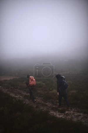 Foto de El senderismo siempre es una buena idea. dos amigos varones haciendo senderismo en las montañas en un día de niebla - Imagen libre de derechos