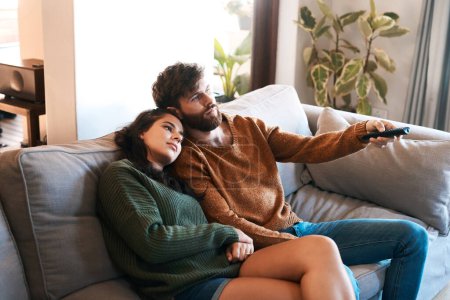Photo for Love, home and relax couple watching tv show, subscription movie or streaming entertainment in living room. Bond, media remote or marriage people watch television, film or video in apartment lounge. - Royalty Free Image