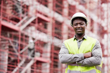 Photo for Portrait of proud black man engineer, construction site and mockup with scaffolding in city, planning and safety. Smile, architect or project manager at building, urban engineering and arms crossed - Royalty Free Image