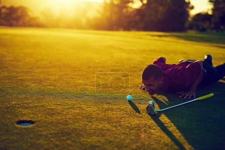 Foto de Preparación pre-putt. un joven mirando el putt durante una ronda de golf - Imagen libre de derechos
