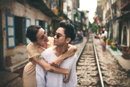 Foto de Aventuras contigo es mi cosa favorita que hacer. una joven pareja compartiendo un momento romántico en las vías del tren en las calles de Vietnam - Imagen libre de derechos