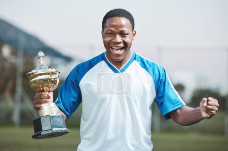 Photo for Sports, soccer player and man celebrate trophy for competition or game outdoor. Portrait of black male athlete champion excited for football prize, award and win or achievement and success on a field. - Royalty Free Image