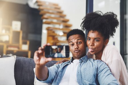 Téléchargez les photos : Les couples qui jouent ensemble restent ensemble. un jeune couple heureux prenant selfies ensemble sur le canapé à la maison - en image libre de droit