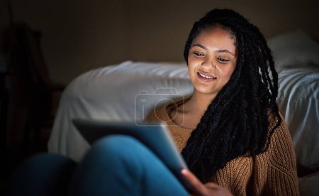 Téléchargez les photos : Refroidi sur le wifi après le travail. une jeune femme détendue utilisant une tablette numérique pendant la soirée à la maison - en image libre de droit