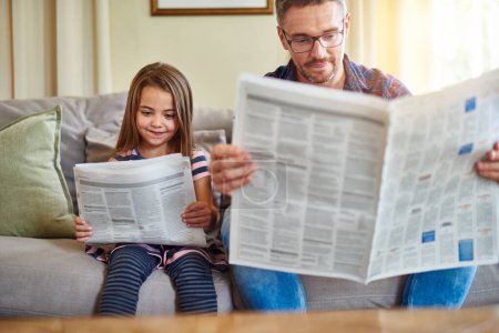 Photo for Father, daughter and reading newspaper on sofa for knowledge, literature or news in living room at home. Happy dad, child and smile for family bonding, learning or education on lounge couch together. - Royalty Free Image