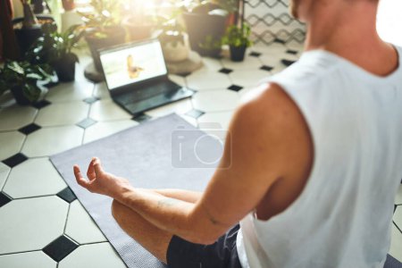 Photo for Channel your inner yogi. an unrecognisable man using a laptop while meditating in the lotus position at home - Royalty Free Image