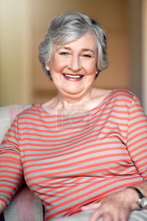 Téléchargez les photos : Maison, heureux et portrait d'une femme âgée avec un sourire pour la retraite et le bonheur des personnes âgées. Détendez-vous, salon et une dame âgée dans une chaise dans le salon avec confiance et confort le matin. - en image libre de droit