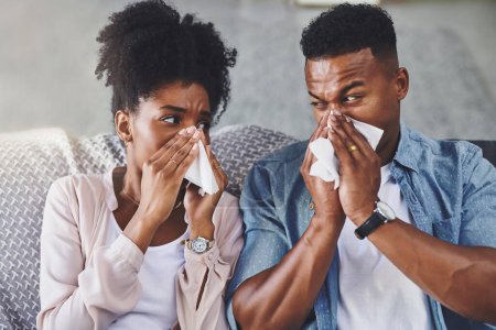 Téléchargez les photos : Qui a donné la grippe à qui ? un jeune couple se mouche sur le canapé à la maison - en image libre de droit