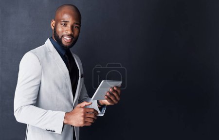 Foto de Nunca hago negocios sin él. Captura de estudio de un hombre de negocios usando una tableta digital sobre un fondo gris - Imagen libre de derechos