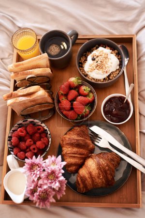 Photo for Breakfast in bed, top view and morning food of croissant, strawberry and drinks for wellness, eating and home cuisine. Hospitality, hotel meal service and tray of bread, coffee and juice in bedroom. - Royalty Free Image