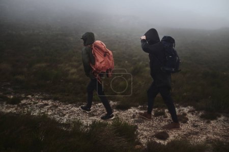 Téléchargez les photos : Étaient déterminés à atteindre la fin de la piste. deux amis masculins sortent pour une randonnée par une journée brumeuse - en image libre de droit