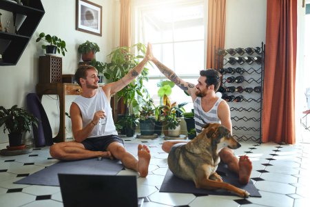 Photo for Health is at the heart of a happy home. two men giving each other a high five after their yoga workout at home - Royalty Free Image