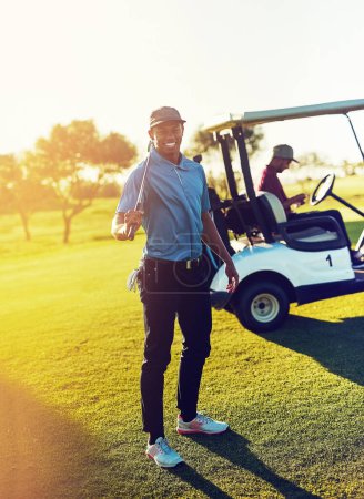 Téléchargez les photos : Il faut beaucoup de balles pour jouer au golf comme moi. un golfeur tenant son club avec un buggy flou en arrière-plan - en image libre de droit