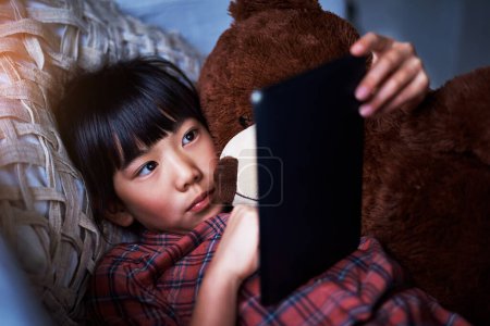 Téléchargez les photos : Le gadget pour les esprits curieux. une petite fille utilisant une tablette numérique à la maison - en image libre de droit