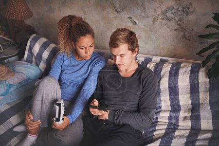 Photo for Anything can be a tool to connect us. a young couple using a smartphone while playing video games on the sofa at home - Royalty Free Image
