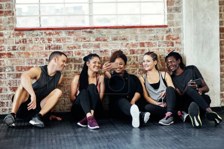 Photo for Fun times in the gym. a cheerful young group of people sitting down on the floor and taking a self portrait together in a gym - Royalty Free Image