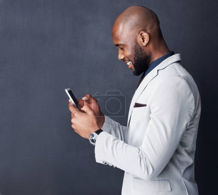 Foto de Conectado instantáneamente a la productividad. Captura de estudio de un hombre de negocios usando un teléfono móvil sobre un fondo gris - Imagen libre de derechos