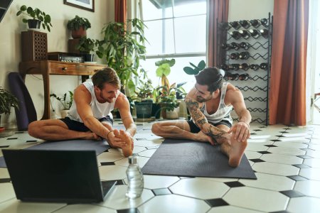 Photo for Everyday is a chance to challenge yourself. two men using a laptop while going through a yoga routine at home - Royalty Free Image